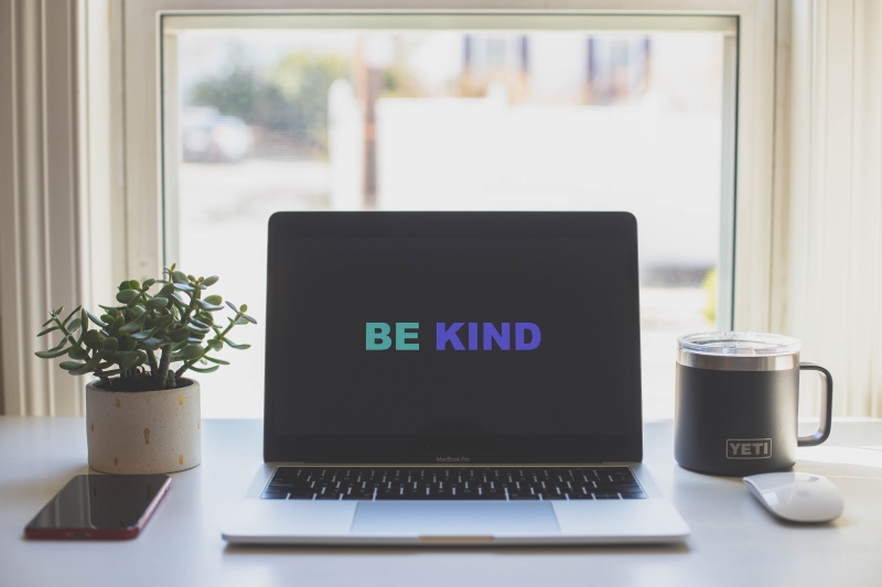 Dator med texten "be kind" på skärmen