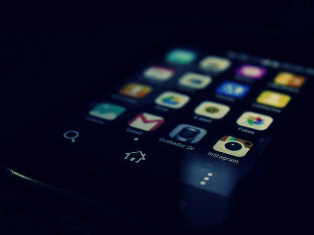 Bilden visar en mobiltelefon med olika appar, bilden är dov och mörk