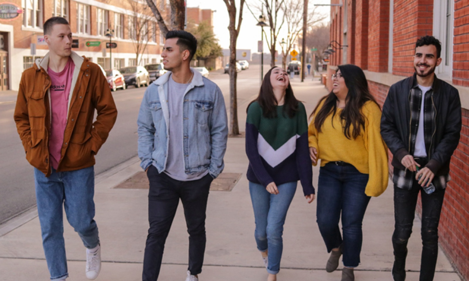 Bilden visar ett gäng med ungdomar som går tillsammans på gatan och samtalar och skrattar
