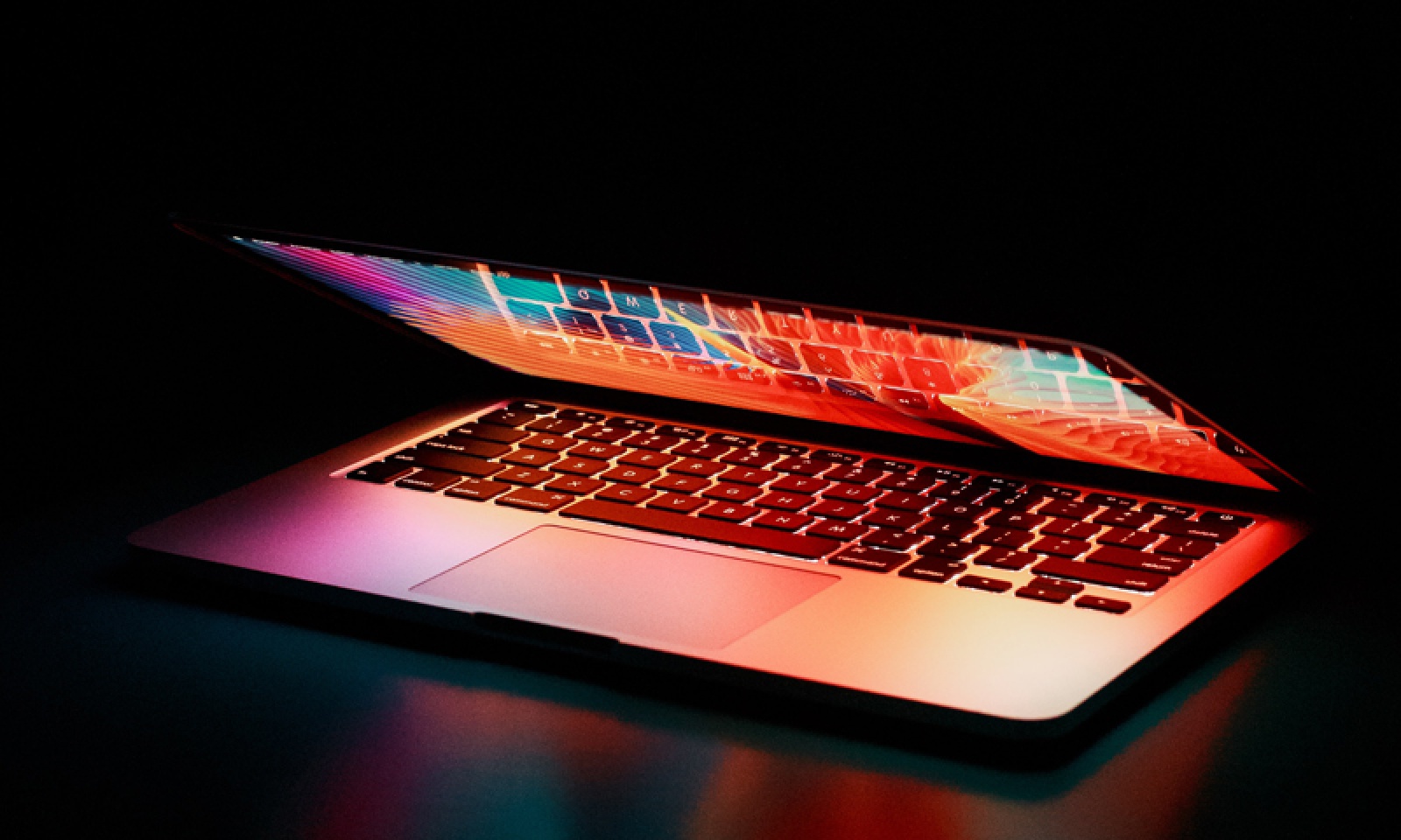 Bilden visar en dator som är halvt öppen där skärmen lyser från datorn och runtomkring är det mörkt