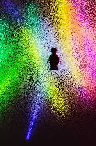 Bilden visar en liten figur av en person som har strålkastarljus i olika färger mot sig